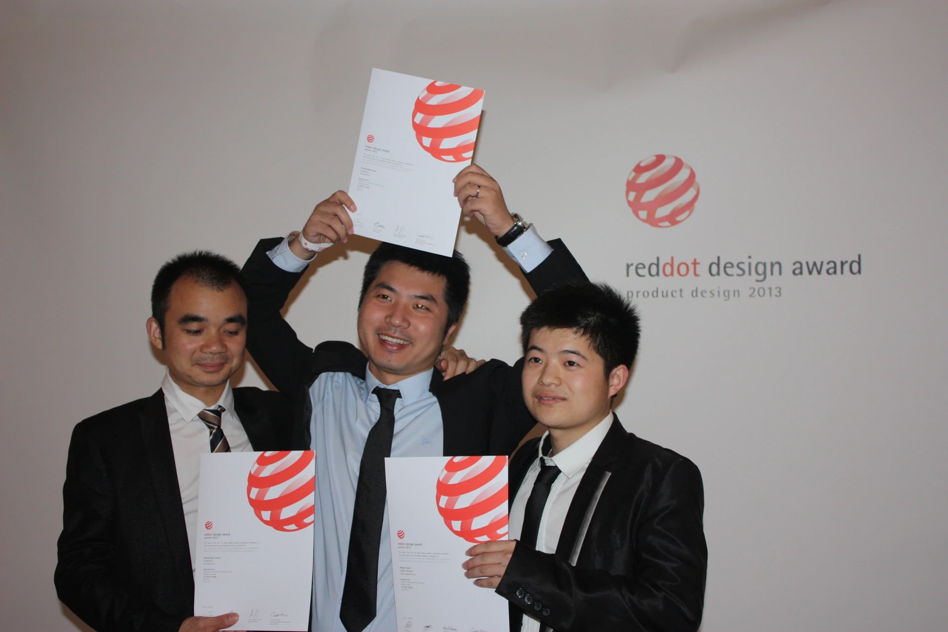 Group celebrating the Red Dot Design Award in 2013, holding original award certificates