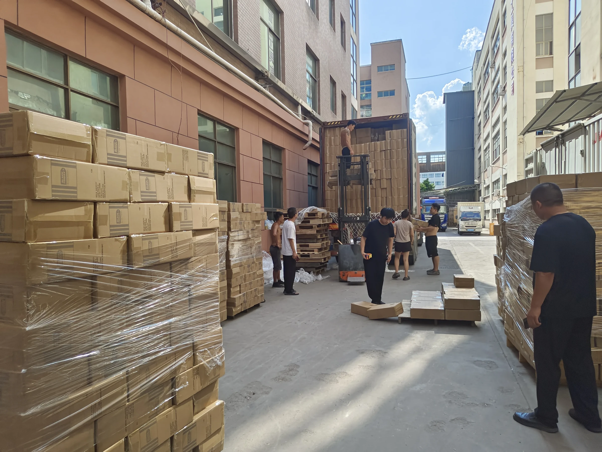 Workers loading boxed goods into a truck outside the factory