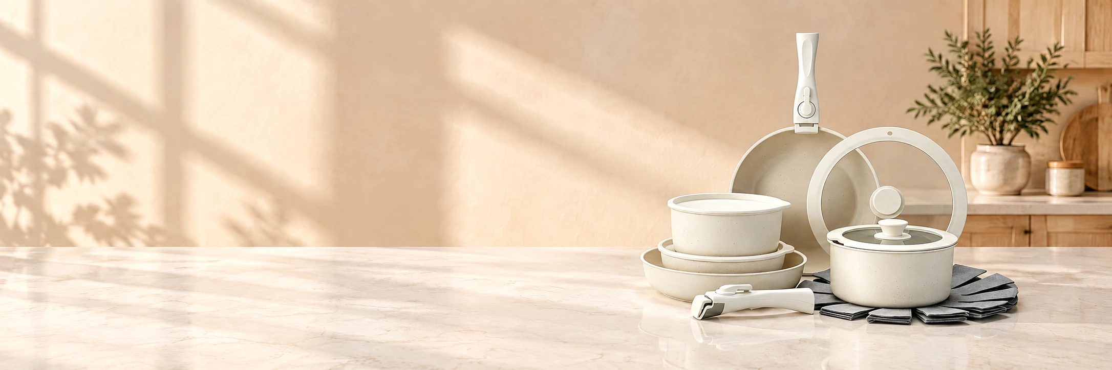 Ivory detachable cookware with glass lids, removable handles and felt protectors on a sunlit kitchen island